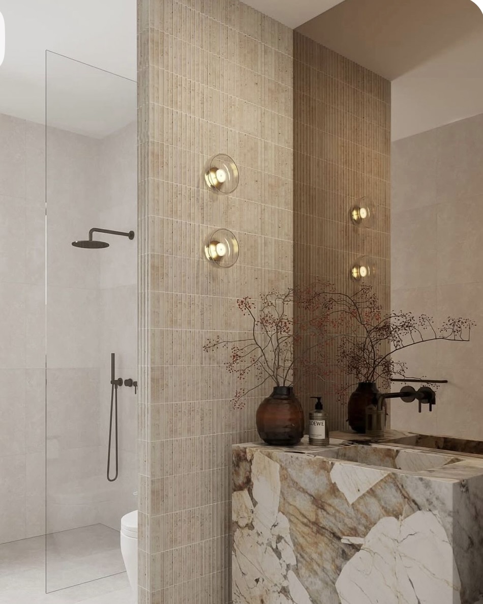 Oakline House powder bath with fluted stone tile and a book-matched marble vanity block